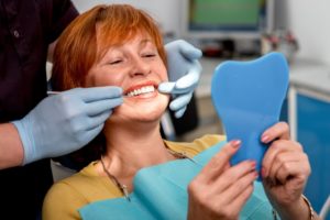 A woman examines her new teeth.